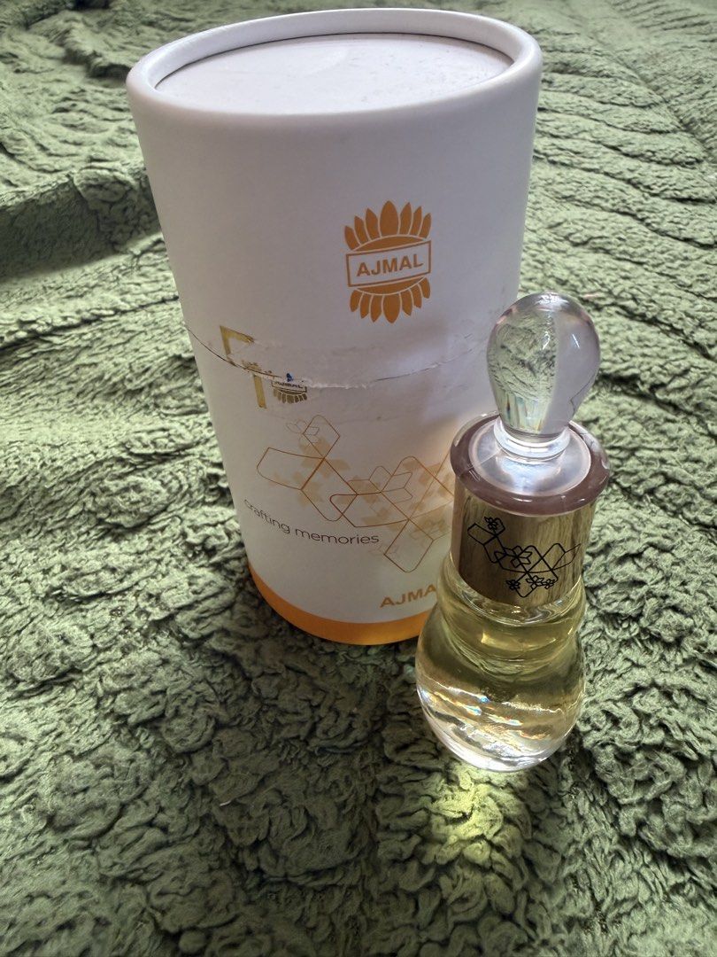 Ajmal - Miss Universe (Category: Fragrance & Deodorants) located in Manila. Submitted by julianna_pm (Listing ID 1466345834, Image 3). Description: Ajmal concentrated perfume oil in an ornate glass bottle. Gold cap with geometric patterns and crystal-like stopper. Includes original white cylindrical packaging with gold branding and graphics. Fragrance oil level is clearly visible inside the bottle. Traditional Middle Eastern attar style. Stored p