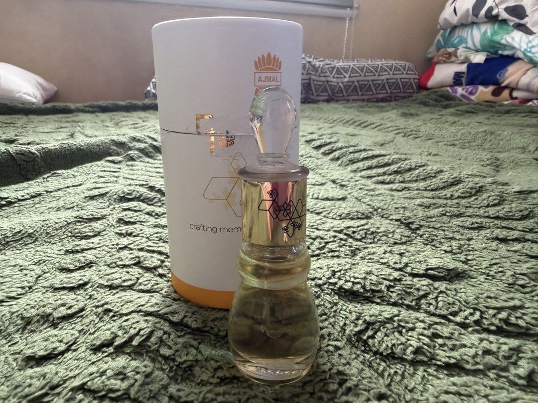 Ajmal - Miss Universe (Category: Fragrance & Deodorants) located in Manila. Submitted by julianna_pm (Listing ID 1466345834, Image 1). Description: Ajmal concentrated perfume oil in an ornate glass bottle. Gold cap with geometric patterns and crystal-like stopper. Includes original white cylindrical packaging with gold branding and graphics. Fragrance oil level is clearly visible inside the bottle. Traditional Middle Eastern attar style. Stored p