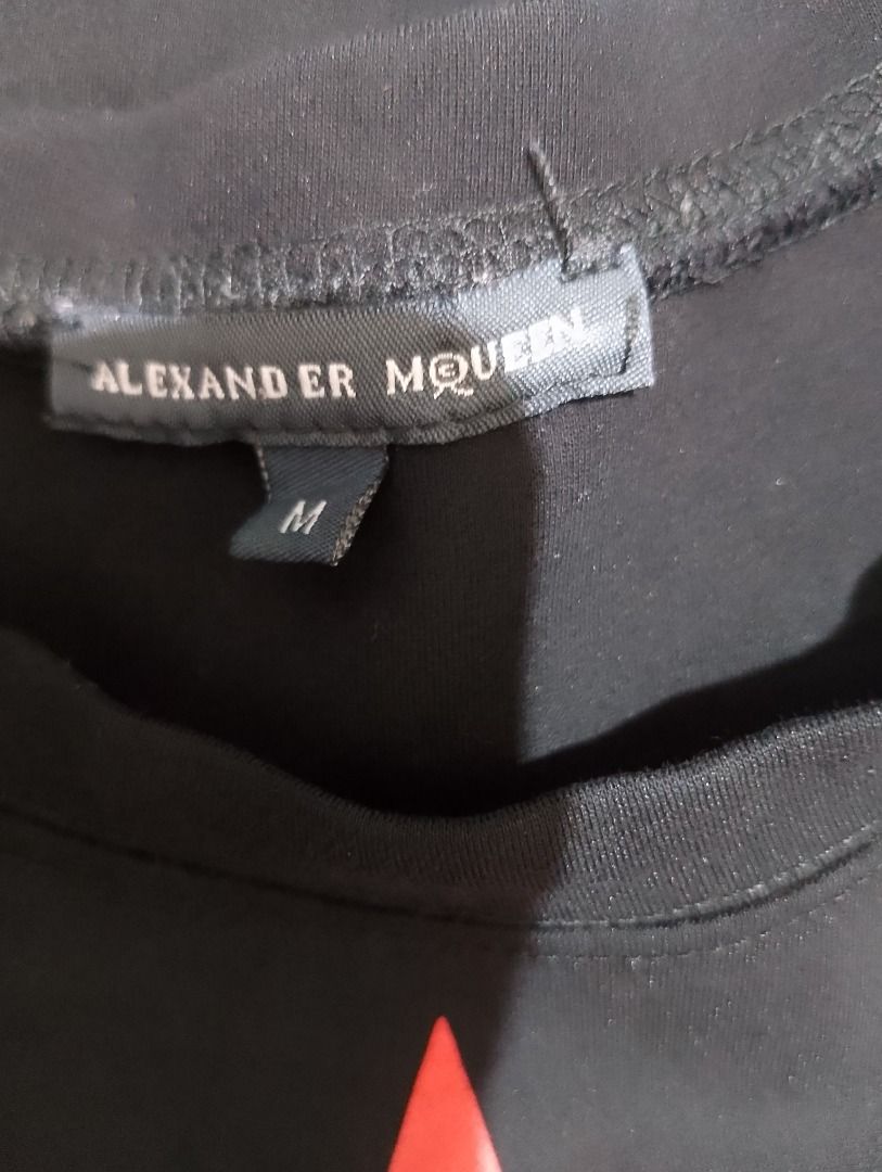 Alexander McQueen black t-shirt size M (Category: Shirts) located in Cavite. Submitted by marvzclothing (Listing ID 1466462093, Image 2). Description: - Brand: Alexander McQueen - Color: Black with red graphic print on the front - Size: M (tag attached at collar) - Condition: Brand new with tags - Care Instructions: Hand wash only, do not tumble dry - Origin: Made in China.