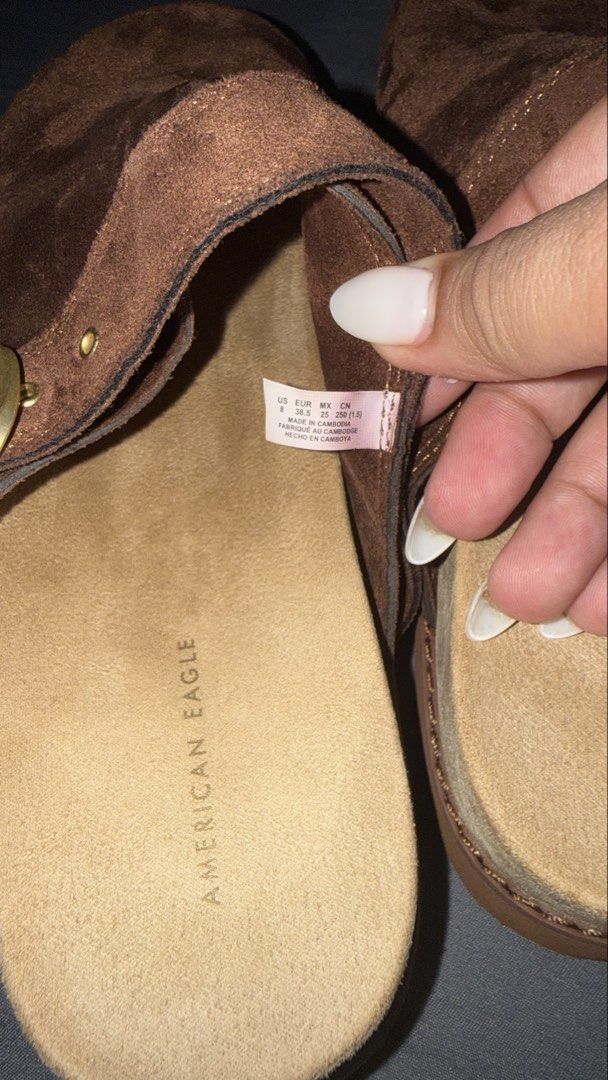 American Eagle Brown Suede Clogs Size 8 (Category: Slippers and slides) located in Andop. Submitted by nobleangel (Listing ID 1466350320, Image 3). Description: - Brand: American Eagle - Style: Slip-on clogs with adjustable side buckle and metallic hardware (Style #6913-200) - Size: US 8 / EUR 38.5 / MX 25 / CN 250 - Material: Suede upper texture with wavy ridged sole pattern underneath - Condition: Clean footbeds with stamped brand logo - Origin