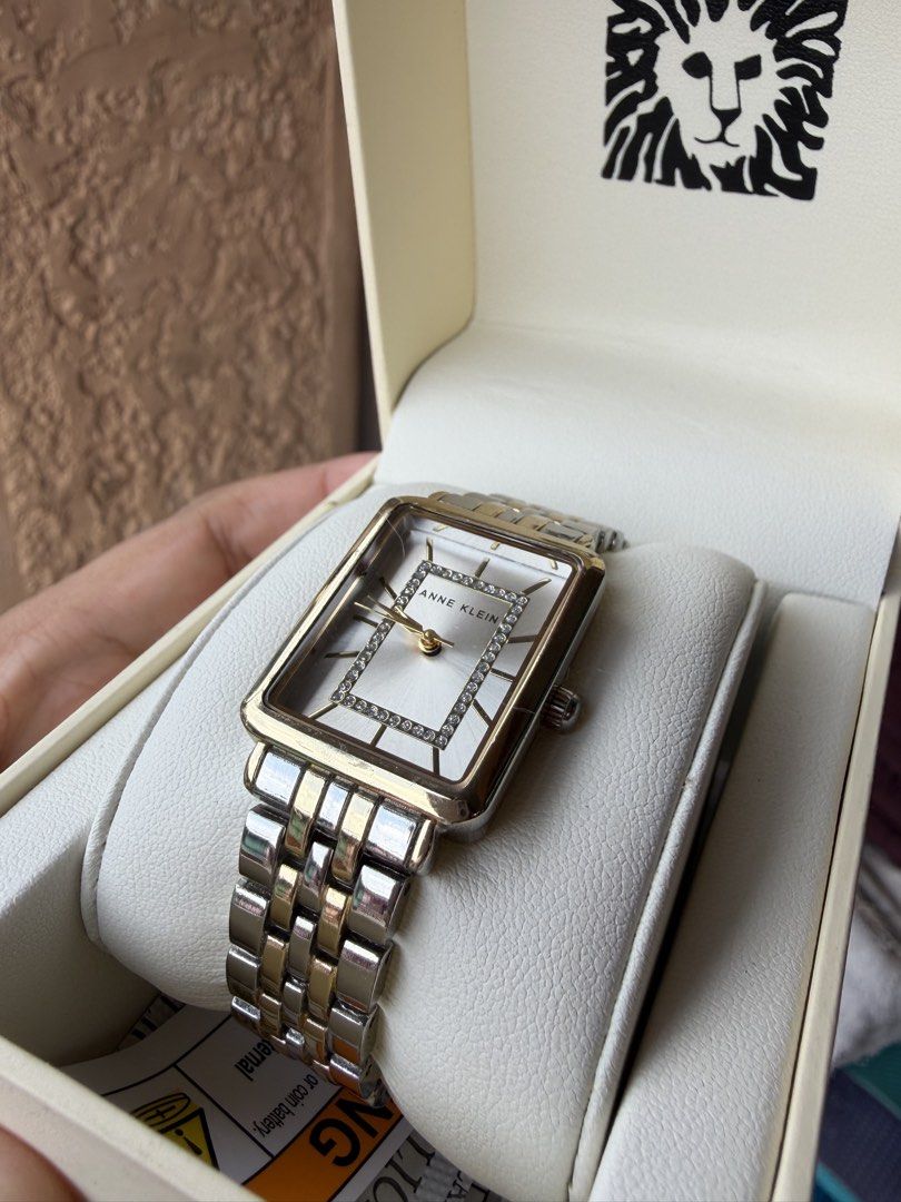 Anne Klein Two-Tone Rectangle Crystal Watch with Box (Category: Women's Watches) located in Manila. Submitted by freeocean-db7e (Listing ID 1466351332, Image 1). Description: - Brand: Anne Klein - Design: Two-tone silver and gold metal bracelet with a classic rectangular case - Dial: White dial with elegant crystal embellishments around the center and gold-tone hands - Inclusions: Original branded box with signature lion logo, cushion holder, and