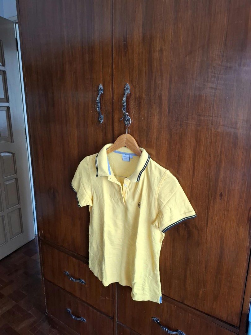 Arrow Yellow Polo Shirt Size L (Category: Tshirts & Polo Shirts ) located in Manila. Submitted by bunbun__ (Listing ID 1466414333, Image 2). Description: - Brand: Arrow - Size: Large (L) - Color: Bright yellow with light blue accent fabric inside the neckline - Details: Contrasting black and white stripes on collar edge and sleeve cuffs - Logo: Small embroidered logo patch on left chest - Closure: Button placket with white buttons - Condition: Ex