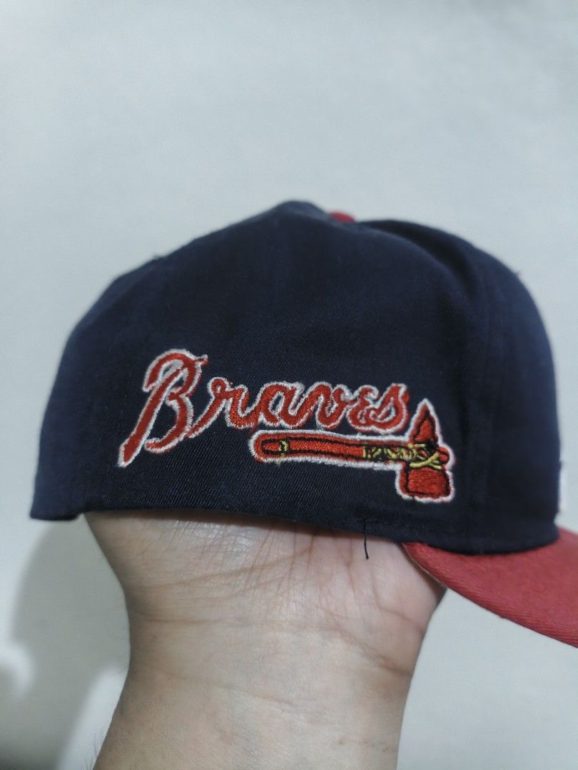 Atlanta Braves MLB Snapback Cap Navy Red (Category: Caps & Hats) located in San Jose. Submitted by ezsenthrift475 (Listing ID 1466351962, Image 3). Description: - Authentic Atlanta Braves snapback cap in navy blue and red - Features embroidered classic 'A' logo on the front and scripted 'Braves' text with tomahawk on the side - Adjustable red plastic snapback closure for a custom fit - Genuine Merchandise label attached inside - Flaw note: White 