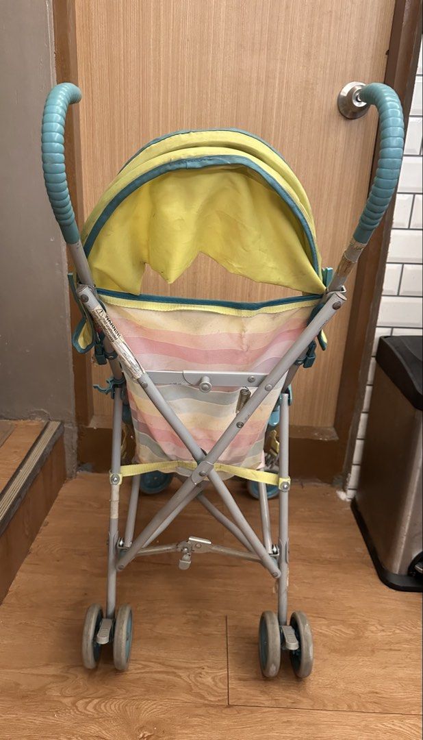 Babyco Stripe Umbrella Stroller (Category: Strollers) located in Quezon City. Submitted by k_prelovedpieces (Listing ID 1466395165, Image 3). Description: - Brand: Babyco - Design: Colorful stripes with bright yellow canopy and teal frame/handles - Type: Lightweight umbrella fold stroller, easy to carry and fits car boots - Safety: Includes attached safety harness - Condition: Shows minor signs of wear and tear on fabric and frame from daily use,