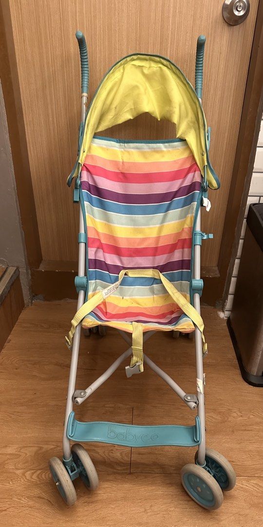 Babyco Stripe Umbrella Stroller (Category: Strollers) located in Quezon City. Submitted by k_prelovedpieces (Listing ID 1466395165, Image 1). Description: - Brand: Babyco - Design: Colorful stripes with bright yellow canopy and teal frame/handles - Type: Lightweight umbrella fold stroller, easy to carry and fits car boots - Safety: Includes attached safety harness - Condition: Shows minor signs of wear and tear on fabric and frame from daily use,