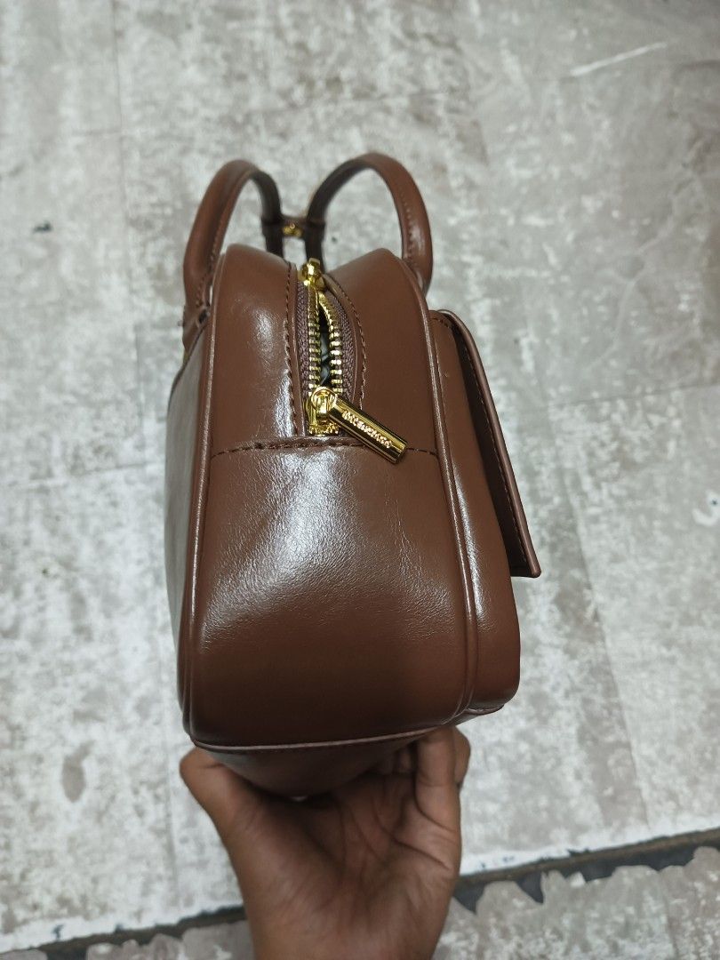 Balenciaga Hourglass Flat Bowling Bag (Category: Luxury Bags & Wallets) located in Baguio. Submitted by brandeditems16 (Listing ID 1466543492, Image 3). Description: - Rich brown leather shoulder bag with a structured rectangular shape - Dual top handles and secure top zipper closure - Eye-catching gold hardware featuring a signature 'B' letter accent on the front pocket - Detailed clean stitching throughout for added durability and style - Great