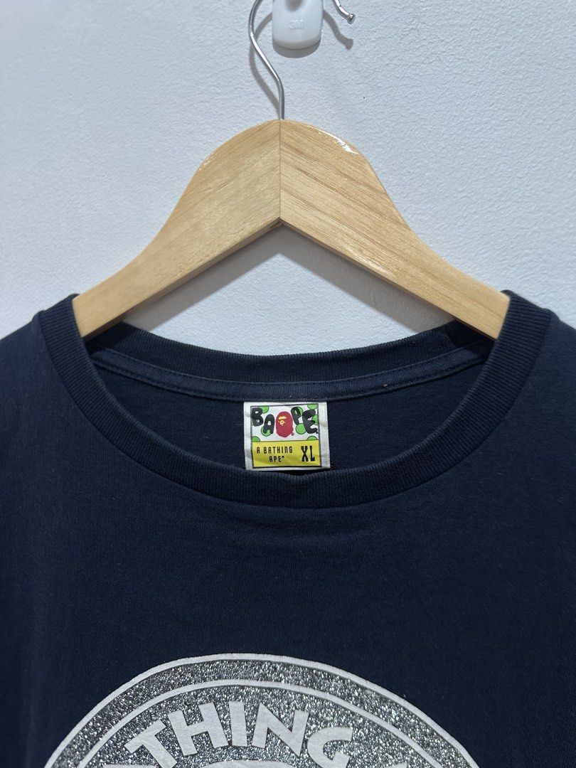 BAPE "Bathing Ape Busy Works" Glittered (Authentic) (Category: Tshirts & Polo Shirts ) located in Manila. Submitted by ylsrarities (Listing ID 1466545701, Image 3). Description: Authentic A Bathing Ape (BAPE) “Busy Works” graphic t-shirt in navy blue. Features the iconic Ape Head circle logo printed with silver glitter text detailing on the front. Brand: A Bathing Ape / BAPE Color: Navy Blue / White / Gold / Silver Glitter Size: XL (Tagged XL / 1