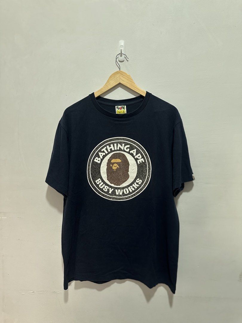 BAPE "Bathing Ape Busy Works" Glittered (Authentic) (Category: Tshirts & Polo Shirts ) located in Manila. Submitted by ylsrarities (Listing ID 1466545701, Image 1). Description: Authentic A Bathing Ape (BAPE) “Busy Works” graphic t-shirt in navy blue. Features the iconic Ape Head circle logo printed with silver glitter text detailing on the front. Brand: A Bathing Ape / BAPE Color: Navy Blue / White / Gold / Silver Glitter Size: XL (Tagged XL / 1