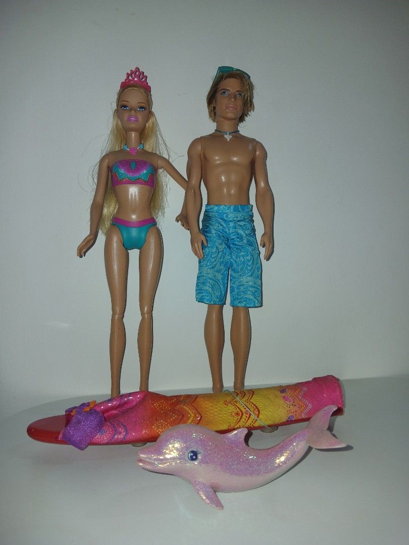 Barbie in a mermaid tail 2 2012 (Category: Kids Toys) located in Subic. Submitted by frncnjntmr22 (Listing ID 1466437805, Image 1). Description: - Barbie and Ken beach doll set - Barbie wears a two-piece swimsuit with pink tiara and necklace - Ken wears blue patterned swim trunks with sunglasses and shark tooth necklace - Includes a vibrant pink surfboard and sparkly pink dolphin toy - Great for imaginative play.
