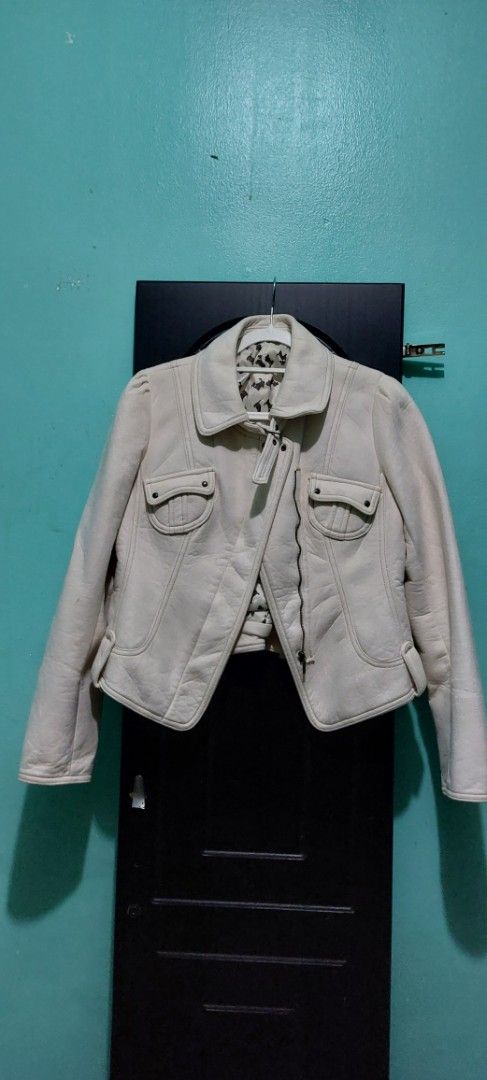 Beige leather jacket (Category: Coats, Jackets and Outerwear) located in Tarlac. Submitted by ramsiap45953 (Listing ID 1466460363, Image 1). Description: - Color: Beige - Material: Leather - Closure: Front zipper - Pockets: Two buttoned chest pockets - Fit: Fitted style with paneled back construction - Details: Adjustable side tabs at the hem, structured collar, and patterned inner lining visible near the collar.