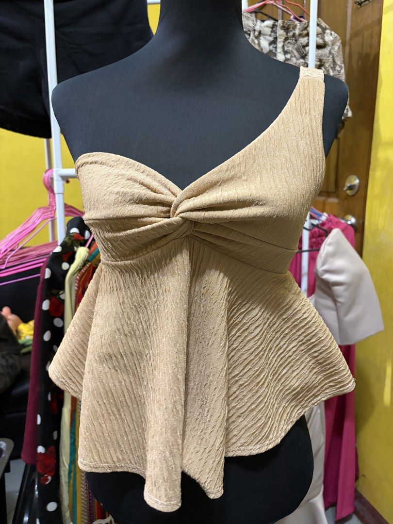 Beige One-Shoulder Twist Front Peplum Top (Category: Sleeveless) located in Calamba. Submitted by handpickedbynetty (Listing ID 1466477504, Image 1). Description: - Color: Beige - Design: One-shoulder with a strapless sweetheart neckline and twisted knot detail at the chest - Fabric: Textured crinkle finish with super stretchy, flattering material - Silhouette: Flared peplum hem starting from the waist - Versatility: Great for casual outings or d