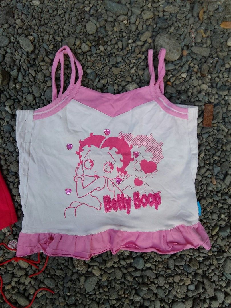 Betty Boop tops bundle Paco Rabanne (Category: Shirts) located in Manila. Submitted by trifted.lootsph (Listing ID 1466462602, Image 2). Description: - Set of 2 cute Betty Boop tops with a trendy Y2K aesthetic - 100% pure cotton material for breathable, all-day comfort - Top 1: Red long-sleeve shirt featuring a Paco Rabanne label, denim pocket detail, and adjustable side tie strings - Top 2: White and pink spaghetti strap camisole with a playful 