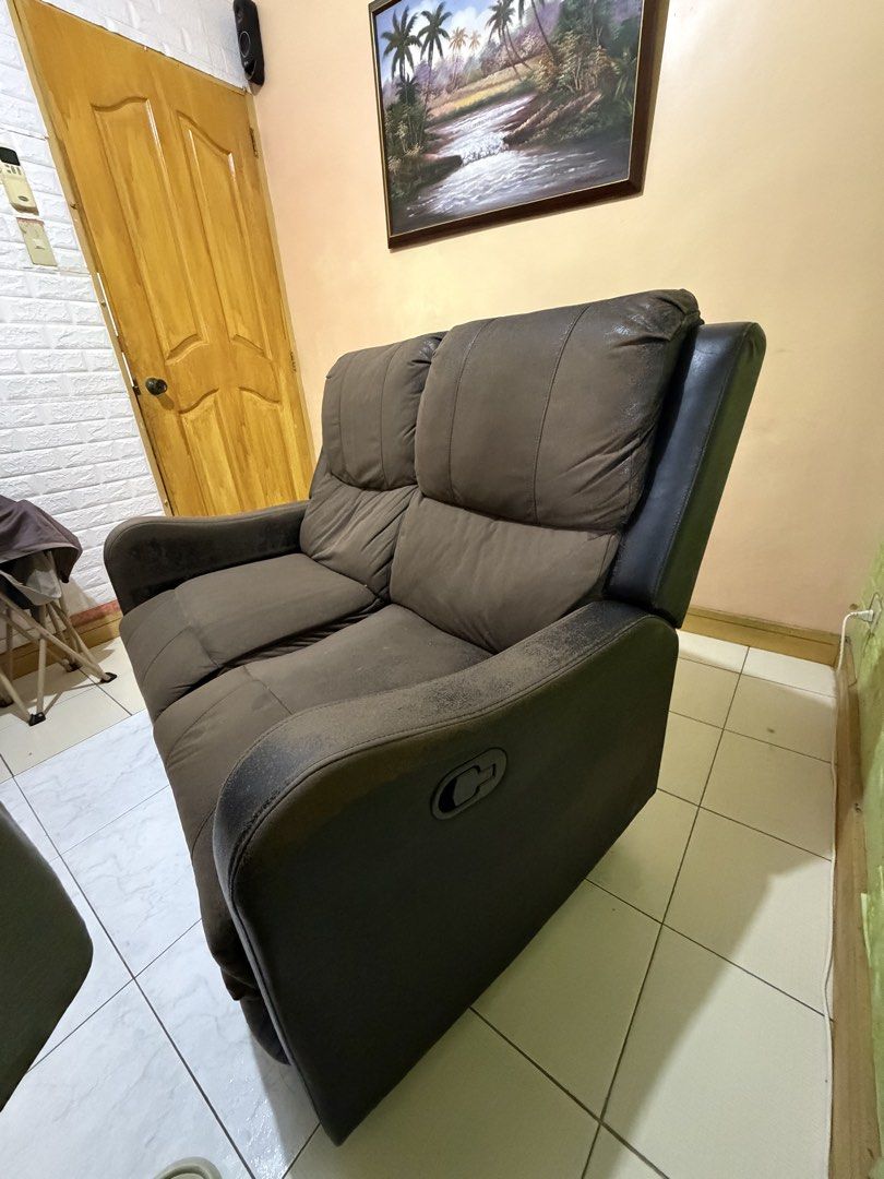 Black 2-Seater Recliner Sofa (Category: Sofas) located in Agdangan. Submitted by eun_zurc (Listing ID 1466469768, Image 2). Description: - Type: Two-seater recliner sofa - Color: Black - Mechanism: Manual pull handle for footrests - Comfort: Plush back cushions and armrests - Condition: Sturdy frame and working recline function, but upholstery has heavy wear, flaking, and peeling on arms, top edges, and footrests - Ideal for: Budget buyers, DIY r