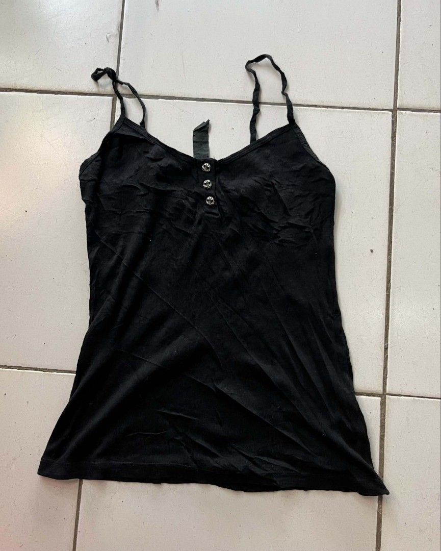 Black camisole tank top with cross patch (Category: Sleeveless) located in Zamboanga. Submitted by 2ndabubazir (Listing ID 1466383932, Image 1). Description: - Color: Black - Material: Soft ribbed cotton knit - Features: Thin spaghetti straps, button-down front with 3 metallic buttons - Unique Details: Leather cross patch on the back and leather brand tag at the neckline - Condition: Pre-loved with general wear, visible fabric lint, and a natural