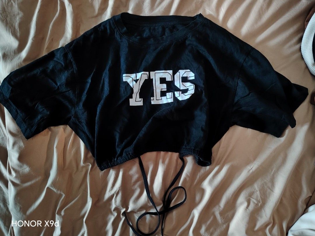 Black Croptop with Graphic and Back Cutout (Category: Shirts) located in Mabalacat. Submitted by Jackikay.PreLoved (Listing ID 1466426641, Image 1). Description: - Size: Small - Semi Large - Color: Black with bold white "YES" graphic on the front - Fit: Oversized boxy and trendy crop top - Details: Cool back cutout and adjustable drawstring hem - Style: Perfect for casual streetwear, easy to pair with high-waisted jeans or skirts.