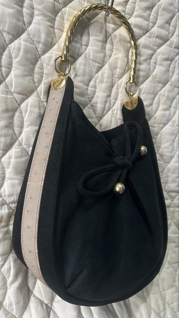 Black Gamuza leather Handbag (Category: Luxury Bags & Wallets) located in Santa Rosa. Submitted by esplanamur03635 (Listing ID 1466388627, Image 2). Description: Chic black suede(gamuza leather) hand/kili bag beige ostrich-textured side panels twisted gold metal top handle. front tie detail with gold accents Perfect for everyday or casual events! (can be worn as shoulder bag -for petite women) Yoshinoya brand original japan bag Classy and excelle