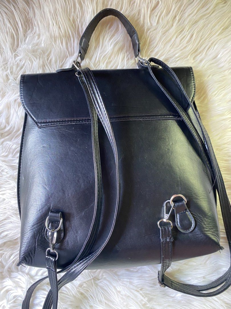 Black leather conversion backpack with silver hardware (Category: Backpacks) located in Manila. Submitted by kimberlyma95836 (Listing ID 1466413308, Image 3). Description: - Material: Smooth faux leather in solid black - Closure: Front flap with metal turn-lock strap detail - Straps: Adjustable with silver-tone lobster clasps and rings, plus back D-rings for versatile strap configurations - Features: Convenient top grab handle and clean stitching