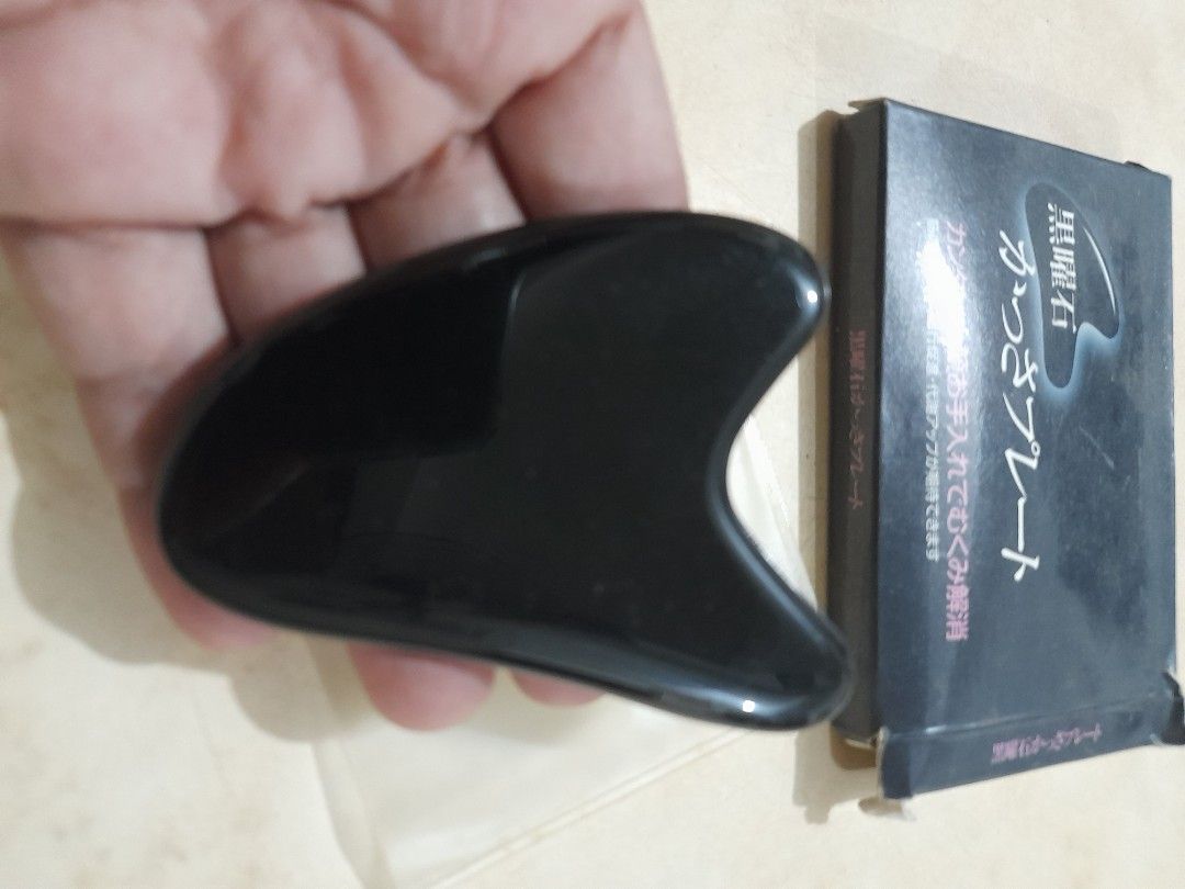 Black Obsidian Gua Sha Facial Tool with Box (Category: Face Care) located in Bocaue. Submitted by marajapansurplus (Listing ID 1466482914, Image 3). Description: - Product: Black Obsidian Gua Sha tool - Benefits: Reduces puffiness, relieves tension, and aids lymphatic drainage - Design: Smooth polished surface with ergonomic curves for face and neck - Condition: Clean, well-maintained - Inclusions: Original black retail box and protective sleeve 