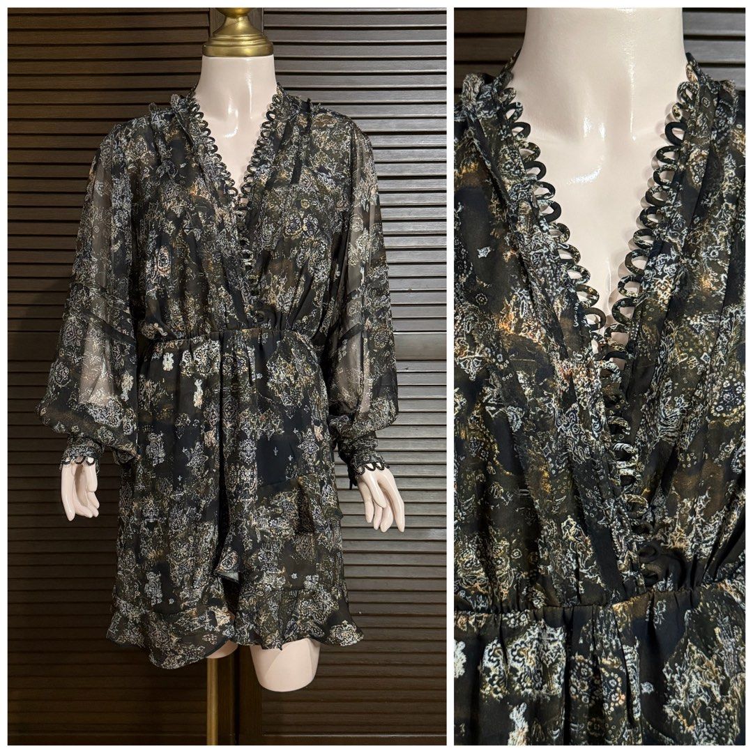 Black patterned chiffon dress with V-neck and ruffled hem (Category: Dresses) located in Santiago. Submitted by jy.collection (Listing ID 1466344267, Image 1). Description: Black long-sleeve chiffon dress, detailed with a patterned print throughout. Deep V-neckline outlined with looped trim detailing. Elastic waist creates a gathered, flowy skirt shape with a ruffled hemline. Balloon sleeves finished with fitted cuffs. Lightweight fabric with a s