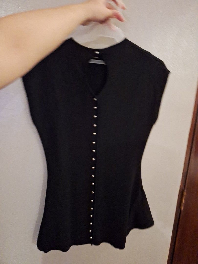 Black sleeveless top with decorative silver buttons down the back (Category: Sleeveless) located in Manila. Submitted by emitakerus08386 (Listing ID 1466479470, Image 2). Description: - Color: Black - Style: Sleeveless top with round neckline and flared, wavy hem - Back Details: Teardrop cutout with a vertical row of small silver round buttons all the way down - Fabric: Smooth texture with great stretch - Condition: Clean, excellent pre-loved con