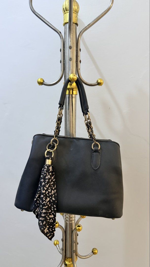 Black structured handbag with chain straps and scarf charm (Category: Shoulder Bags) located in Manila. Submitted by laxamanapa81165 (Listing ID 1466538952, Image 2). Description: - Color & Material: Black textured structured handbag - Straps: Dual handles combining leather-look material and gold-tone chains - Accessories: Includes a detachable black-and-white patterned twilly scarf - Interior/Base: Spacious main compartment with a sturdy base an