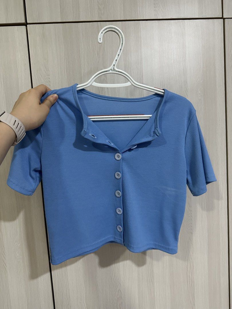 Blue Ribbed Crop Top Short Sleeve Button Down (Category: Shirts) located in Paranaque City. Submitted by elenyuloque (Listing ID 1466462037, Image 1). Description: - Color: Blue - Style: Ribbed crop top with short sleeves and fold-down collar - Details: Functional button-down front with 5 matching buttons - Material: Soft, textured, and stretchy fabric - Condition: Clean and ready to wear - Styling tip: Great basic piece to pair with high-waisted