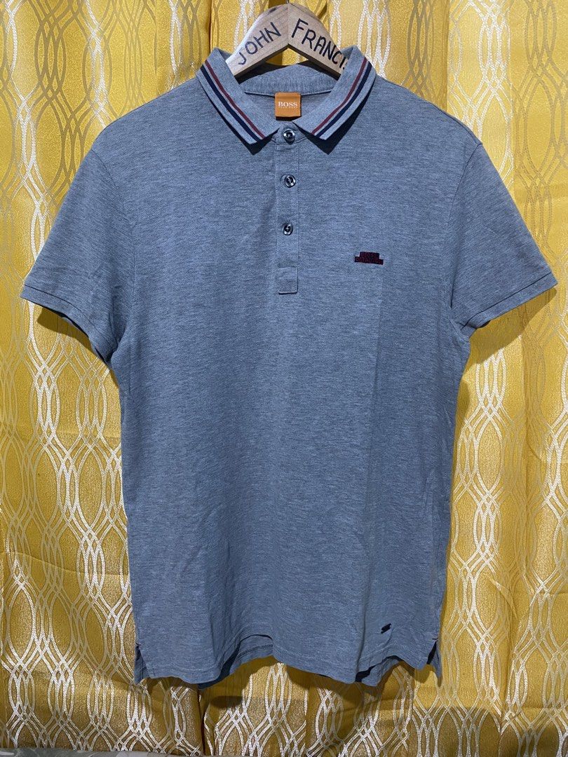 Boss Orange Grey Polo Shirt Size M (Category: Tshirts & Polo Shirts ) located in Manila. Submitted by jfrancis18 (Listing ID 1466355721, Image 2). Description: Grey Boss Orange polo shirt in size M. Short sleeves, classic three-button placket. Striped collar detail in red and navy. Embroidered logo patch on the chest, plus a small metal brand plaque near the hem. Soft cotton fabric, breathable and comfortable. Great basic for casual wear or smart