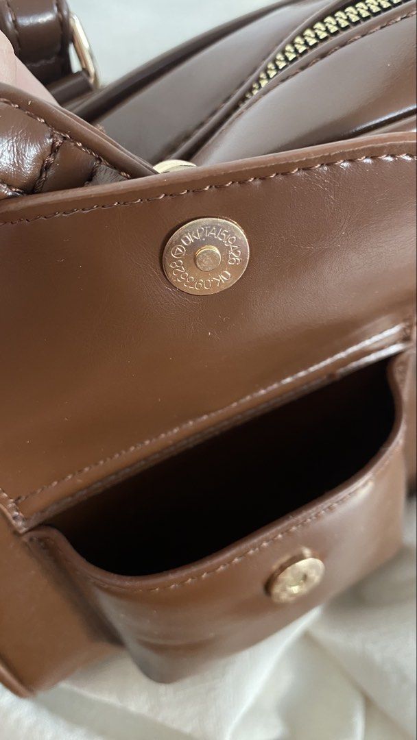 Bostanten Brown Shoulder Bag With Front Pockets (Category: Luxury Bags & Wallets) located in Manila. Submitted by poliin (Listing ID 1466430434, Image 2). Description: - Brand: Bostanten - Color: Dark brown - Material: Smooth faux leather with chic gold hardware - Closure: Secure top zip closure with double top handles - Pockets: Two convenient front pockets with snap button closures, plus an interior zipper pocket - Interior: Clean black fabric 