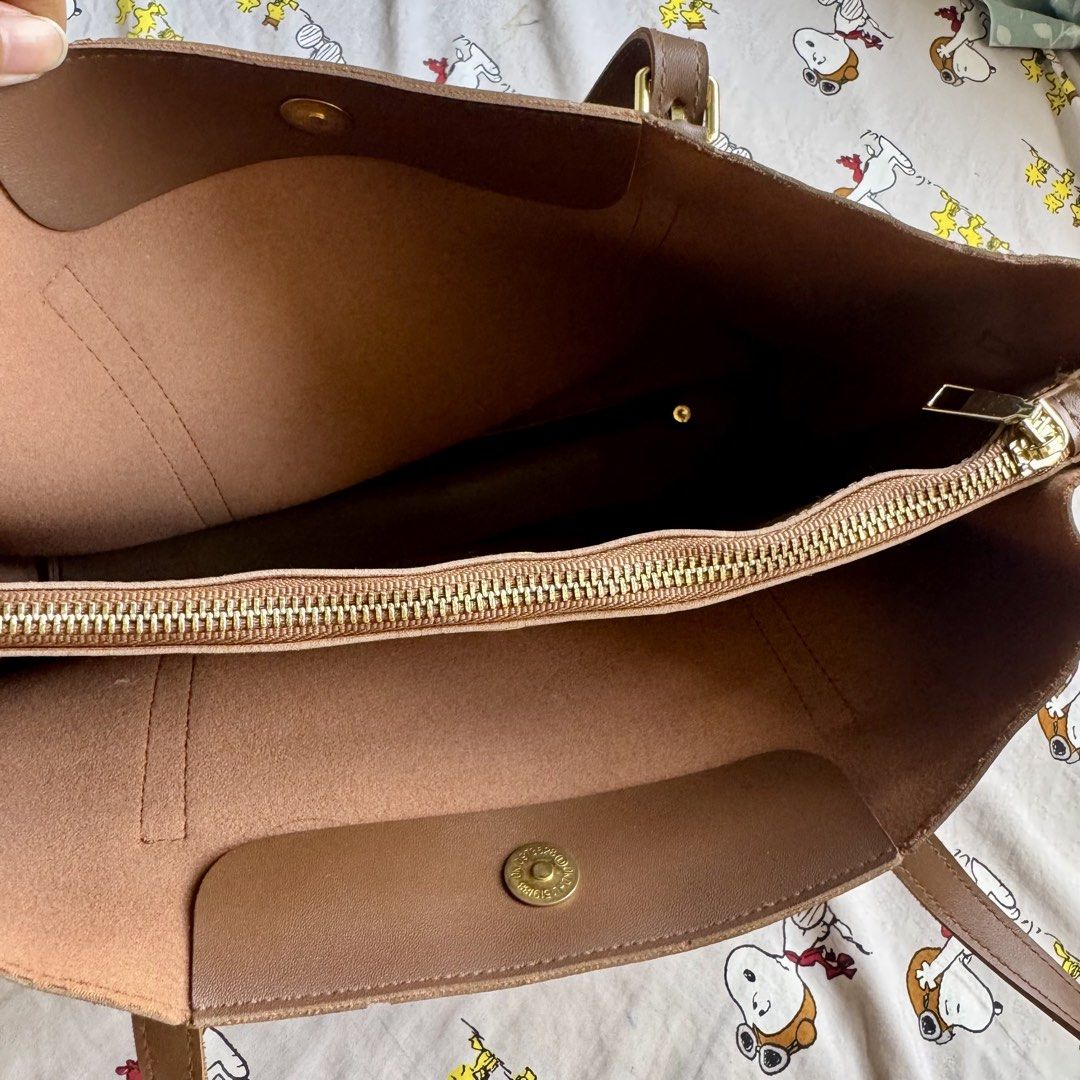 Brown Leather Tote Bag with Gold Hardware (Category: Tote Bags) located in Marikina City. Submitted by preloved_n_reloved (Listing ID 1466413662, Image 2). Description: - Material: Smooth brown faux leather with clean interior lining - Closure: Secure top zip closure plus a magnetic button tab - Hardware: Elegant gold buckles on front straps and protective bottom metal feet - Straps: Comfortable double shoulder straps for easy daily wear - Style: