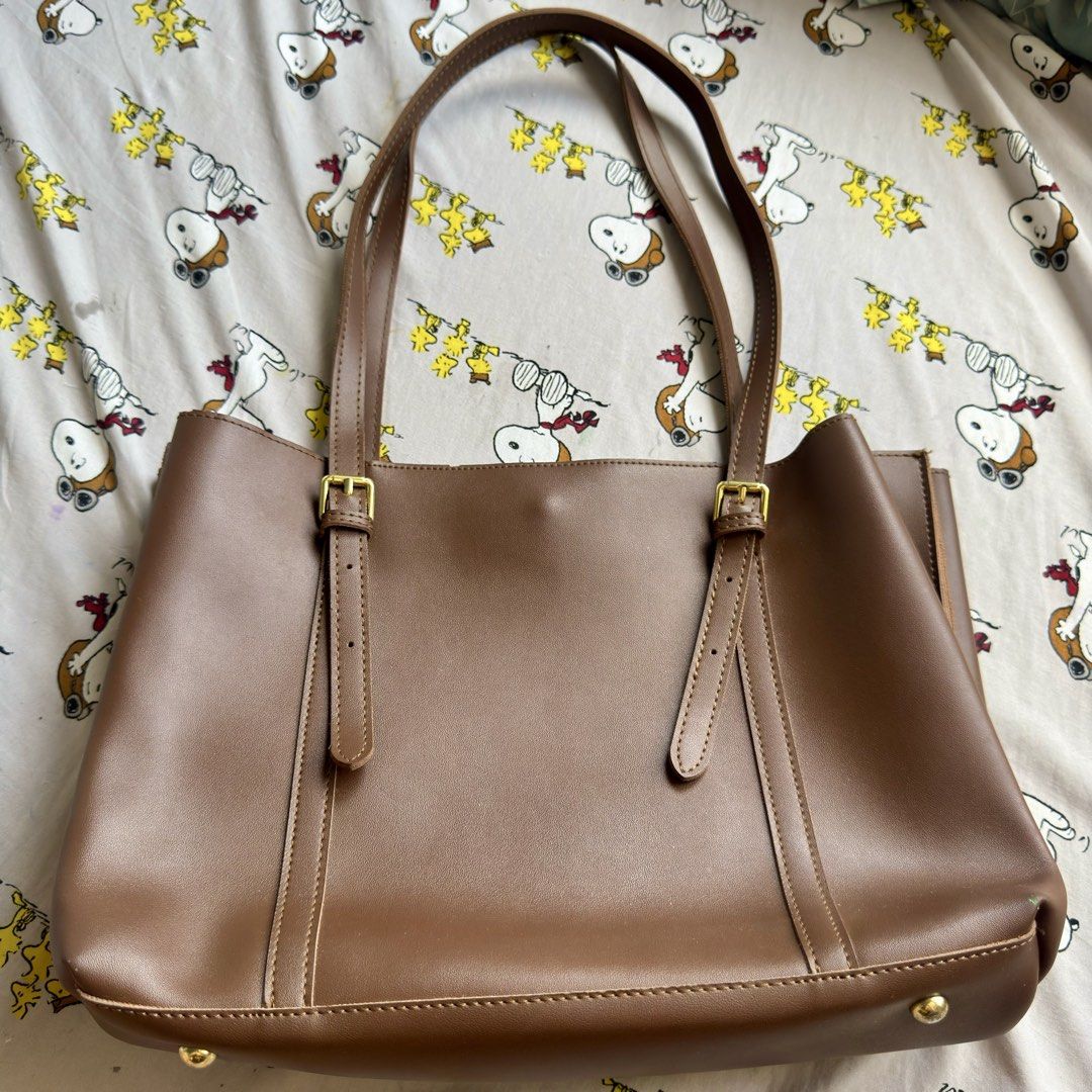 Brown Leather Tote Bag with Gold Hardware (Category: Tote Bags) located in Marikina City. Submitted by preloved_n_reloved (Listing ID 1466413662, Image 1). Description: - Material: Smooth brown faux leather with clean interior lining - Closure: Secure top zip closure plus a magnetic button tab - Hardware: Elegant gold buckles on front straps and protective bottom metal feet - Straps: Comfortable double shoulder straps for easy daily wear - Style: