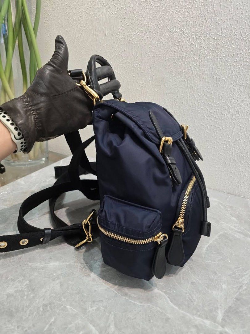 Burberry Nylon Rucksack Backpack Navy Blue (Category: Backpacks) located in Baao. Submitted by jodelmancera21 (Listing ID 1466358401, Image 2). Description: - Authentic Burberry navy blue nylon backpack - Luxurious black leather top handle and trim details - Elegant gold-tone hardware throughout - Secure front flap with buckle closures and drawstring pull - Convenient front zipper pocket and side pockets - Comfortable quilted back panel with adju