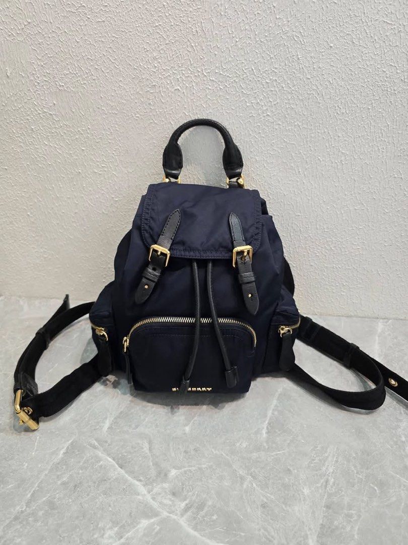 Burberry Nylon Rucksack Backpack Navy Blue (Category: Backpacks) located in Baao. Submitted by jodelmancera21 (Listing ID 1466358401, Image 1). Description: - Authentic Burberry navy blue nylon backpack - Luxurious black leather top handle and trim details - Elegant gold-tone hardware throughout - Secure front flap with buckle closures and drawstring pull - Convenient front zipper pocket and side pockets - Comfortable quilted back panel with adju