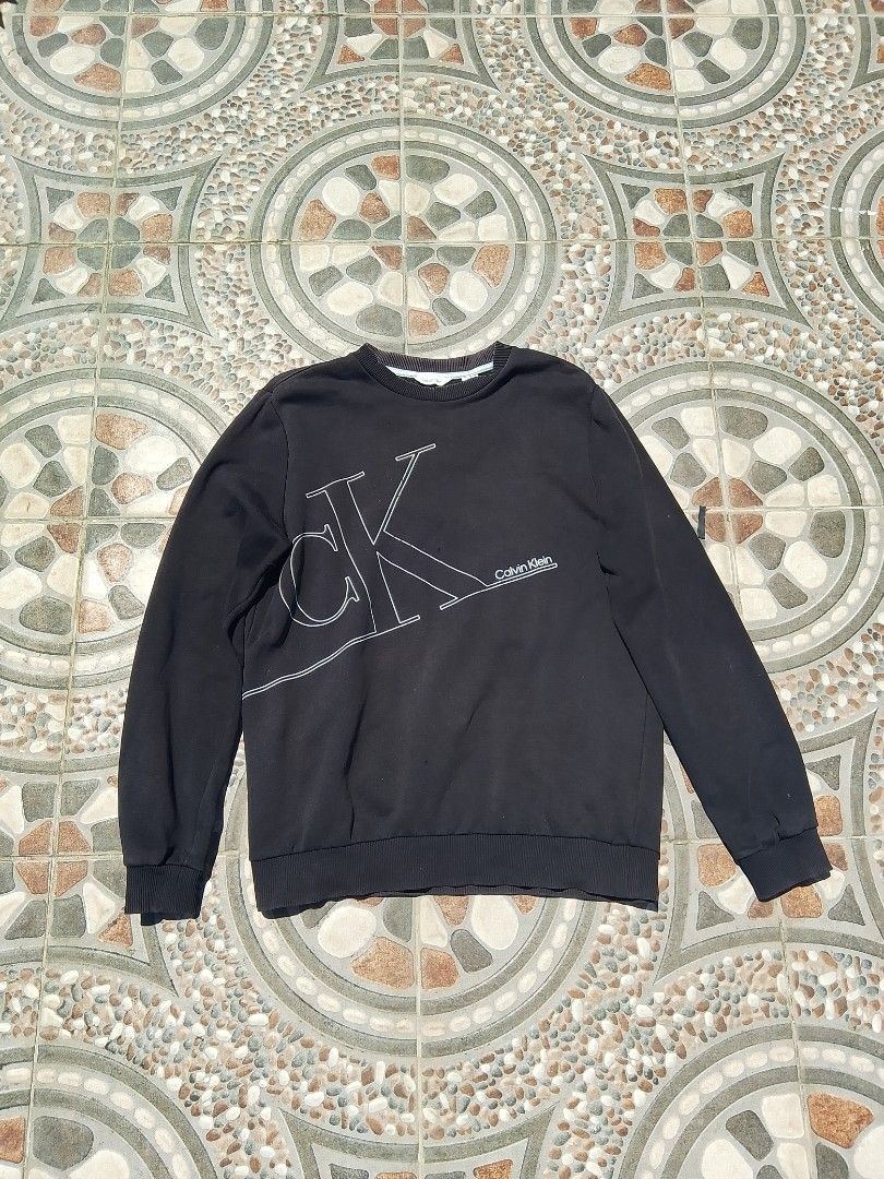 Calvin Klein Black Long Sleeve Sweatshirt (Category: Coats, Jackets and Outerwear) located in Cabuyao City. Submitted by kyokiiiiiii (Listing ID 1466383385, Image 1). Description: - Brand: Calvin Klein - Color: Black with large white chest logo - Style: Long sleeve pullover sweatshirt with standard fit - Details: Ribbed cuffs, collar, and hem for extra comfort - Condition: Great casual piece, perfect for cooler weather - payment first -Shipping f