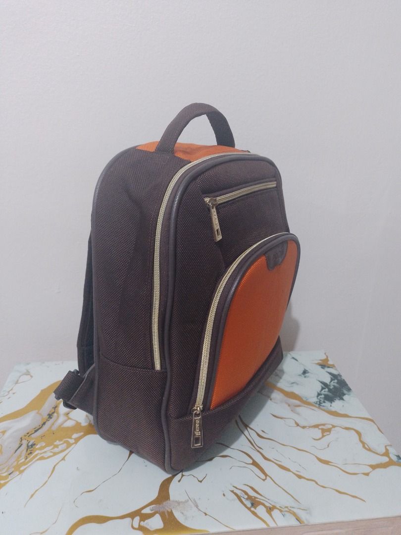 Camji Kids Backpack (Category: Backpacks) located in Imus. Submitted by bestfinds_yeth0724 (Listing ID 1466381484, Image 2). Description: - Brand: Camji - Color: Brown and orange with gold-tone hardware - Material: Textured fabric construction - Storage: Front zipper pocket and large main compartment - Interior: Bright yellow lining with an inner slip pocket - Comfort: Padded shoulder straps and top grab handle - Condition: Clean inside and out N