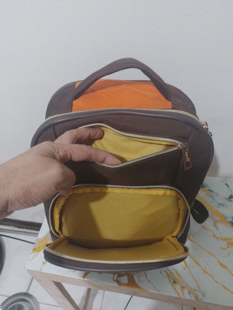 Camji Kids Backpack (Category: Backpacks) located in Imus. Submitted by bestfinds_yeth0724 (Listing ID 1466381484, Image 3). Description: - Brand: Camji - Color: Brown and orange with gold-tone hardware - Material: Textured fabric construction - Storage: Front zipper pocket and large main compartment - Interior: Bright yellow lining with an inner slip pocket - Comfort: Padded shoulder straps and top grab handle - Condition: Clean inside and out N