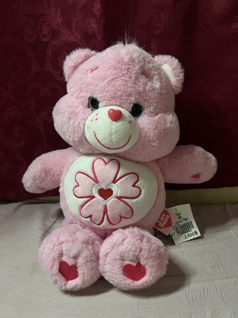 Care Bears Cherry Blossom Pink Bear Plush (Category: Plushies & Soft Toys) located in Bulacan. Submitted by haven_plushie_dolls.888 (Listing ID 1466398666, Image 1). Description: - Official pink Care Bears plush toy - Features a cute cherry blossom flower belly badge - Sweet heart details on feet and red heart on hip - Original tags and store barcode attached - Made with ultra-soft and fluffy material - Clean, pristine condition (from a smoke-fre