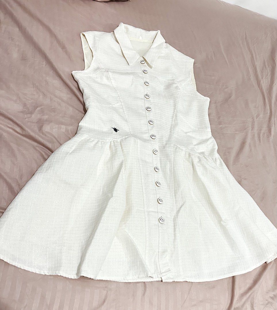 CD Cream Sleeveless Collared Button-Down Dress with Bee Embroidery CD buttons (Category: Dresses) located in Manila. Submitted by everythingsale101 (Listing ID 1466441040, Image 2). Description: - Color: Light Cream - Style: Sleeveless collared dress with dropped waist and flared pleated skirt - Details: Full front button closure featuring luxury CD monogram hardware on every button - Accent: Distinct black bee embroidery on the right side - Fabr