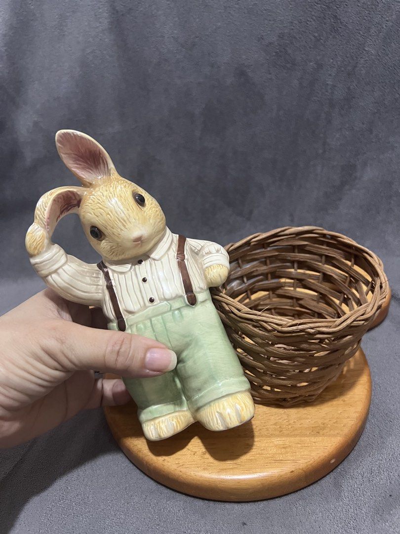 Ceramic Rabbit Figurine with Woven Basket Holder (Category: Designer & Blind Box Toys) located in Las Pinas. Submitted by maple0305 (Listing ID 1466413726, Image 3). Description: - Adorable ceramic rabbit figurine wearing a striped shirt and green overalls - Stands approx. 5.5 inches tall on a sturdy round wooden base - Features a charming design with one ear held up and an attached mini woven wicker basket - Perfect decorative piece for Easter, 