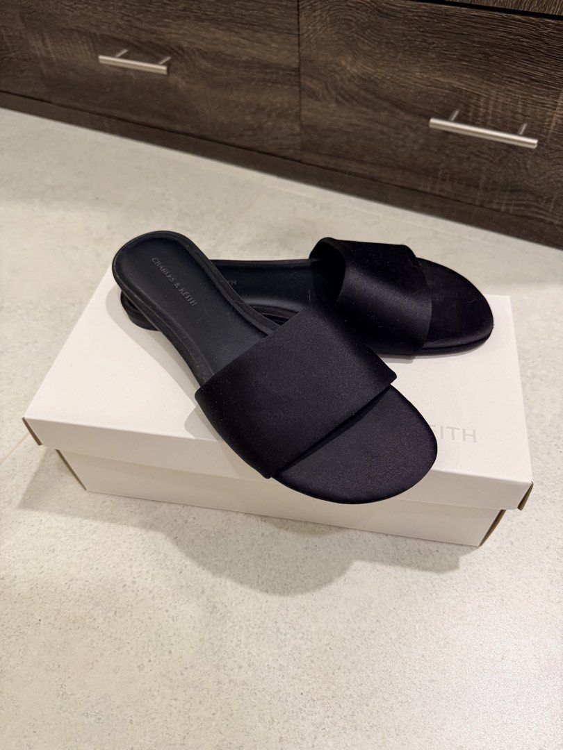 Charles & Keith Black Textured Slides Size 38 (Category: Flats & Sandals) located in Las Pinas. Submitted by felicianoh40332 (Listing ID 1466531898, Image 1). Description: - Brand: Charles & Keith - Style: Black textured slides with a sleek satin-like wide strap - Size: 38 - Design: Slip-on, open toe, flat soles - Condition: Worn a few times; slight dust and minor wear on soles - Inclusion: Original white shoebox.