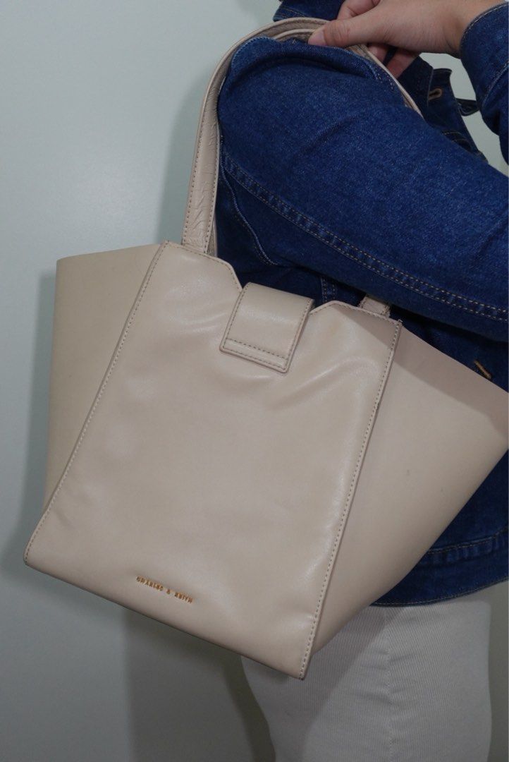 Charles & Keith Cream Tote Bag (Category: Tote Bags) located in Manila. Submitted by renkacoleni (Listing ID 1466523168, Image 1). Description: - Brand: Charles & Keith - Color: Cream - Material: Smooth faux leather - Design: Structured winged silhouette with gold foil embossed logo - Closure: Magnetic clasp with distinct brass hardware - Condition: Clean interior and exterior finish.