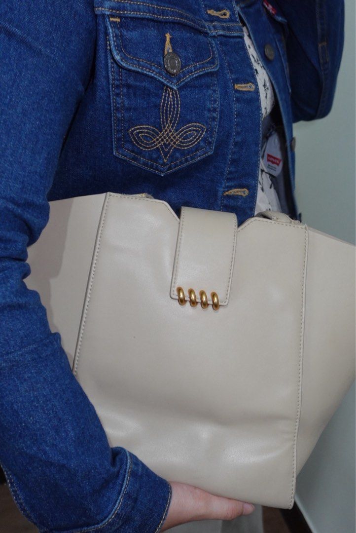 Charles & Keith Cream Tote Bag (Category: Tote Bags) located in Manila. Submitted by renkacoleni (Listing ID 1466523168, Image 3). Description: - Brand: Charles & Keith - Color: Cream - Material: Smooth faux leather - Design: Structured winged silhouette with gold foil embossed logo - Closure: Magnetic clasp with distinct brass hardware - Condition: Clean interior and exterior finish.