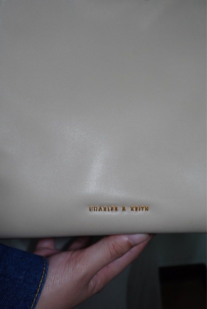 Charles & Keith Cream Tote Bag (Category: Tote Bags) located in Manila. Submitted by renkacoleni (Listing ID 1466523168, Image 2). Description: - Brand: Charles & Keith - Color: Cream - Material: Smooth faux leather - Design: Structured winged silhouette with gold foil embossed logo - Closure: Magnetic clasp with distinct brass hardware - Condition: Clean interior and exterior finish.
