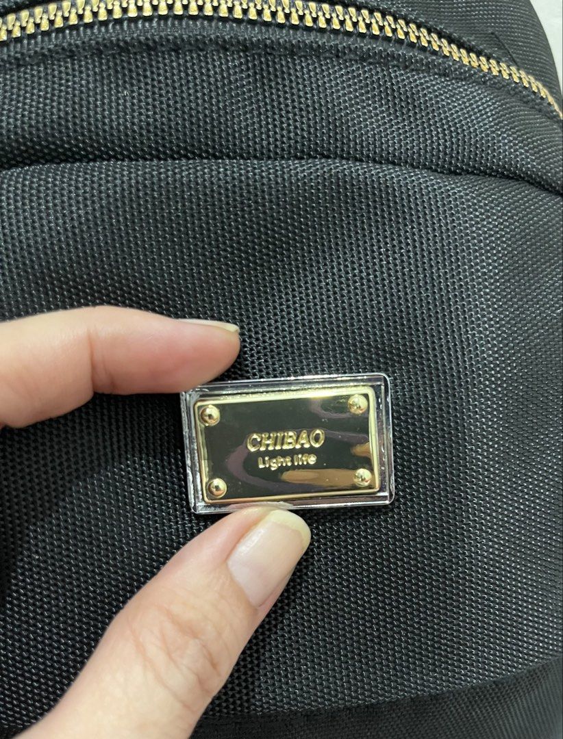 CHIBAO Black Nylon Mini Backpack Gold Hardware (Category: Backpacks) located in Talisay. Submitted by cherylu (Listing ID 1466536311, Image 2). Description: Black nylon backpack from CHIBAO with gold-toned metal accents. Front zipped pocket and main compartment. Signature branded fabric lining inside with extra slip and zip pockets. Adjustable straps feature woven CHIBAO lettering. Clean hardware and sturdy fabric construction throughout..