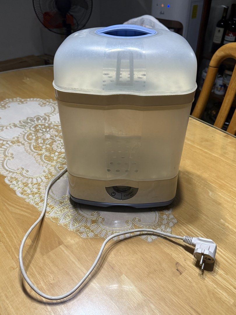 Chicco Compact Eco Bottle Sterilizer (Category: Breastfeeding & Bottle Feeding) located in Caloocan City. Submitted by kc_kylie (Listing ID 1466563375, Image 1). Description: - Brand: Chicco - Type: Compact baby bottle sterilizer - Color/Design: Clear plastic body with blue lid handle and embossed Chicco branding - Features: Internal rack tray and front-panel power button - Inclusions: Power cord and plug - Condition: Used item with normal wear o