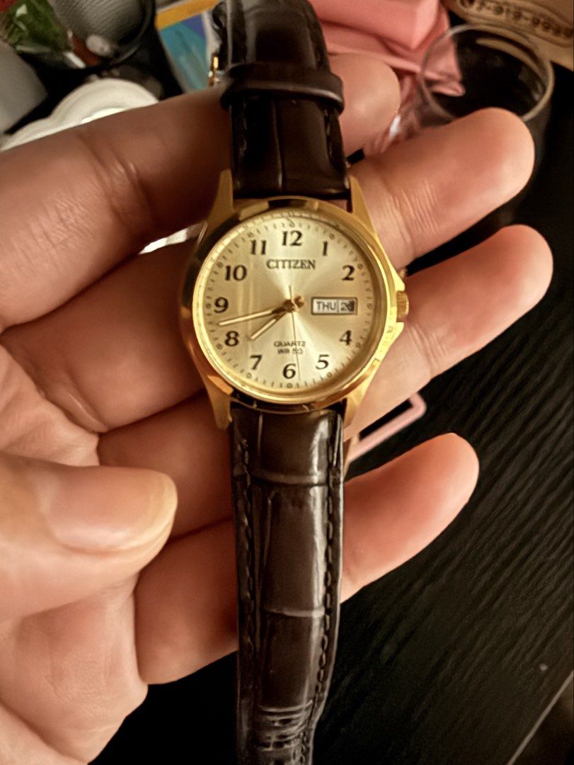 Citizen Ladies Watch EQ2002-07P (Category: Women's Watches) located in Manila. Submitted by jdeaellaaaa (Listing ID 1466563171, Image 2). Description: - Brand/Model: Citizen EQ2002-07P Ladies Watch - Design: Elegant gold-tone case with a dark brown leather strap - Dial: Classic champagne dial with easy-to-read Arabic numerals - Features: Convenient day-date window at the 3 o'clock position - Movement: Reliable quartz movement - Water Resistance: 