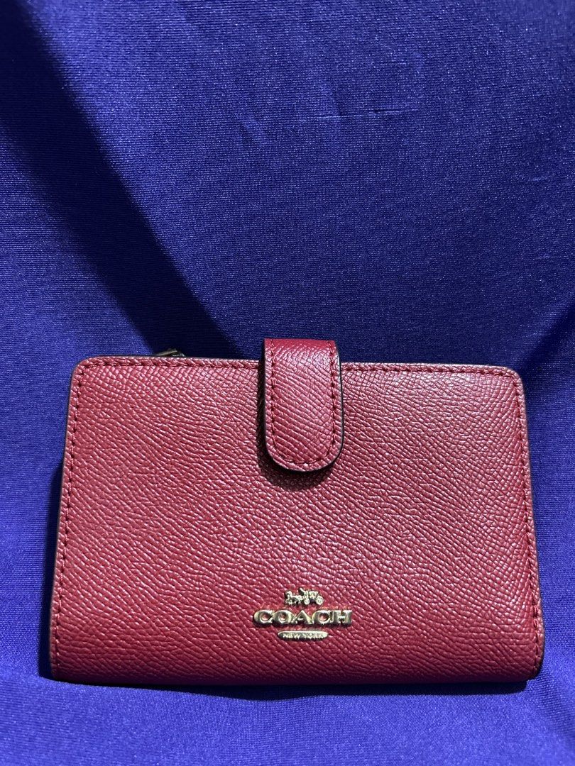 Coach Red Leather Medium Wallet (Category: Wallets & Card holders) located in Cavite. Submitted by mgstuffboutique (Listing ID 1466466290, Image 1). Description: - Brand: Coach New York - Material: Red pebbled leather with gold-toned hardware - Closure: Secure snap strap - Interior features: ID window, multiple card slots, and zippered section for coins/bills - Design: Structured, clean lining, and compact size that easily fits in smaller bags - 