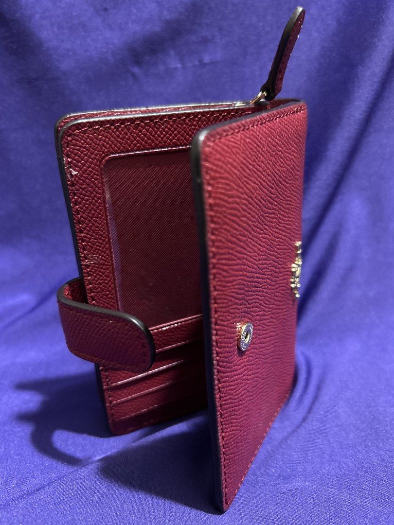 Coach Red Leather Medium Wallet (Category: Wallets & Card holders) located in Cavite. Submitted by mgstuffboutique (Listing ID 1466466290, Image 2). Description: - Brand: Coach New York - Material: Red pebbled leather with gold-toned hardware - Closure: Secure snap strap - Interior features: ID window, multiple card slots, and zippered section for coins/bills - Design: Structured, clean lining, and compact size that easily fits in smaller bags - 