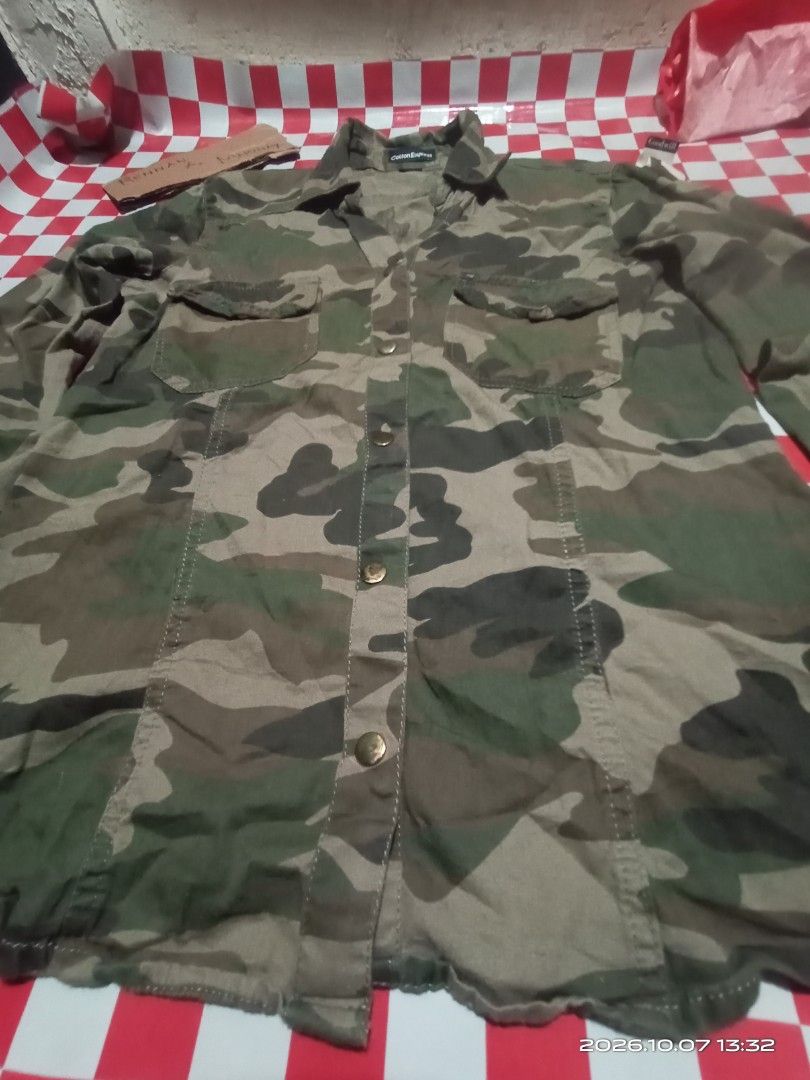 Cotton Express Camouflage Long Sleeve Button-Down Shirt (Category: Longsleeves) located in Danao, Cebu. Submitted by rennan.546 (Listing ID 1466408293, Image 3). Description: - Brand: Cotton Express dimention 22x17 issue none color rate 10/10 loc danao city Cebu city - Design: Green and brown camouflage print - Style: Utility shirt, perfect for casual days - Details: Button-up front, two chest pockets, collared neck with brass-tone buttons - Slee