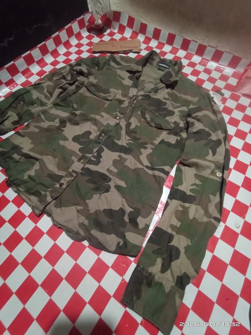 Cotton Express Camouflage Long Sleeve Button-Down Shirt (Category: Longsleeves) located in Danao, Cebu. Submitted by rennan.546 (Listing ID 1466408293, Image 2). Description: - Brand: Cotton Express dimention 22x17 issue none color rate 10/10 loc danao city Cebu city - Design: Green and brown camouflage print - Style: Utility shirt, perfect for casual days - Details: Button-up front, two chest pockets, collared neck with brass-tone buttons - Slee