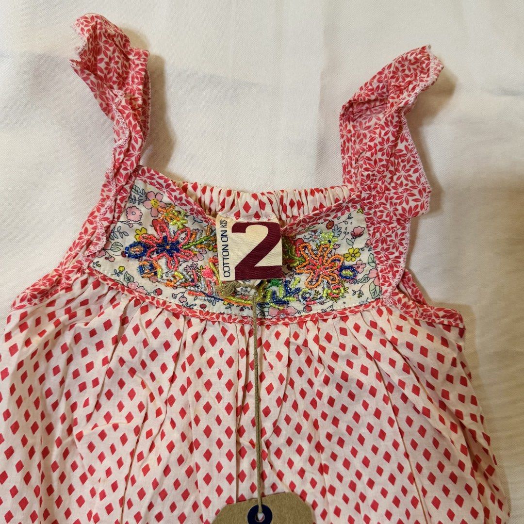 Cotton On Dress (Category: Babies & Kids Fashion) located in Paranaque City. Submitted by dionne_bird (Listing ID 1466514336, Image 2). Description: - Brand: Cotton On Kids - Size: 2 - Design: Red and white diamond print with floral embroidered neckline and colorful beaded details - Straps: Ruffled sleeveless straps - Material: Lightweight cotton, ideal for warm weather - Condition: Brand new with tag attached.